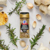 A bottle of McCormick Smoky Garlic &amp; Rosemary Finishing Salt is surrounded by garlic cloves and rosemary sprigs.