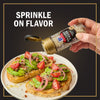 A hand sprinkles McCormick Balsamic &amp; Herb Finishing Salt onto avocado toast with tomatoes and red onions.