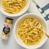 Two bowls of spaghetti with a sprinkle of McCormick Zesty Lemon Finishing Salt.