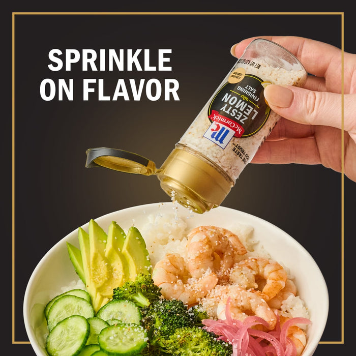 A hand sprinkles McCormick Zesty Lemon Finishing Salt onto a bowl of shrimp rice avocado cucumber broccoli and pickled onions.