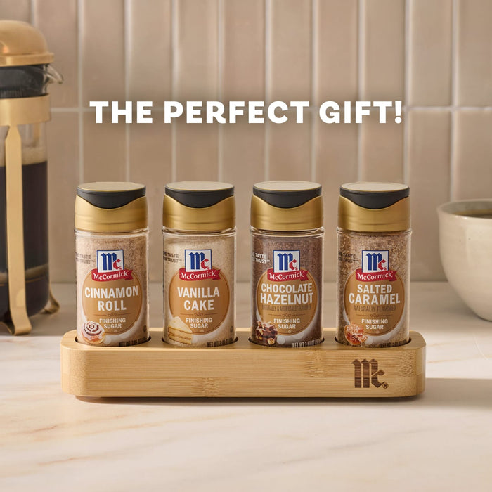 The Mccormick Finishing Sugar Caddy 4Ct is presented as the perfect gift, featuring four flavors-Cinnamon Roll, Vanilla Cake, Chocolate Hazelnut, and Salted Caramel-arranged in a wooden holder on a kitchen counter.