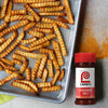 A tray of crinkle-cut french fries is displayed next to a bottle of Lawry's Seasoning Salt.