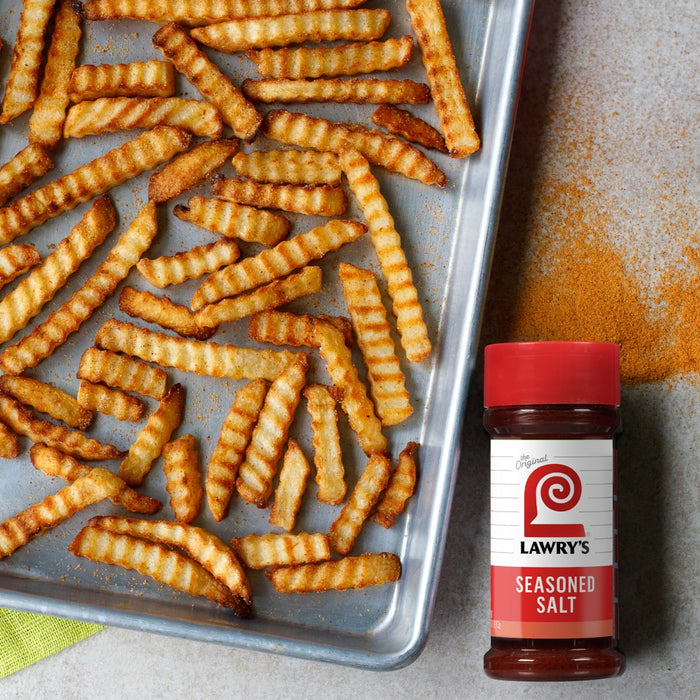 A tray of crinkle-cut french fries is displayed next to a bottle of Lawry's Seasoning Salt.