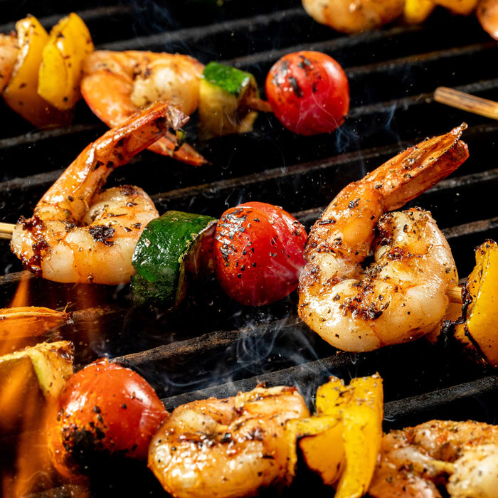Grilled shrimp skewers with vegetables on a barbecue grill.