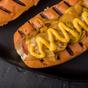 A delicious hot dog is topped with grilled onions and mustard on a toasted bun.