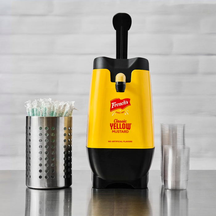A dispenser of Frenchs Classic Yellow Mustard with a stack of plastic cups and a utensil holder.