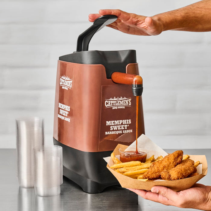 A hand pours Cattlemens Memphis Sweet BBQ sauce onto a plate of french fries and chicken tenders.