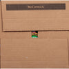 A close-up of a brown cardboard box with a McCormick All Mate can peeking out from the top.