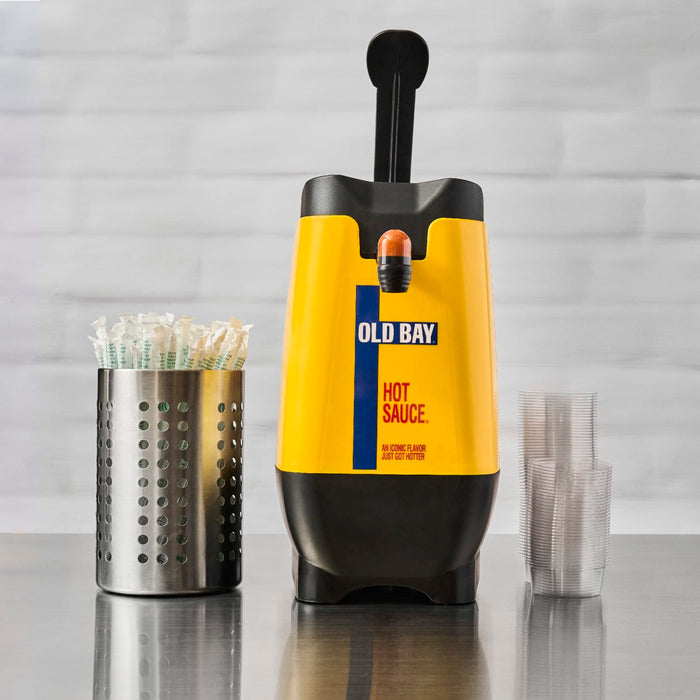A yellow Old Bay hot sauce dispenser with a black top and a silver utensil holder with green straws.