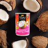 A can of Thai Kitchen coconut whipping cream is surrounded by halved coconuts.