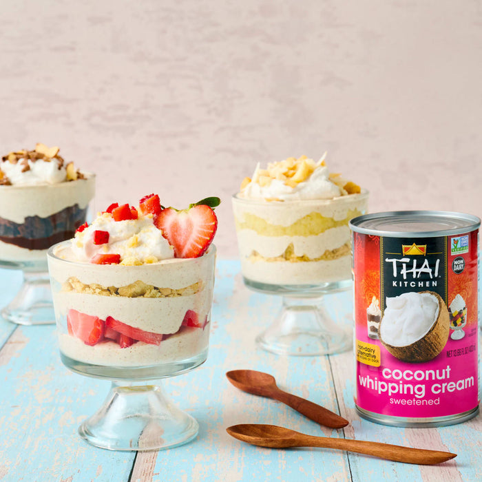 This is an image of Thai Kitchen coconut whipping cream next to three dessert cups filled with layers of cream fruit and other toppings.