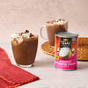 A can of Thai Kitchen coconut whipping cream is featured next to two glasses of hot chocolate topped with whipped cream and chocolate shavings.