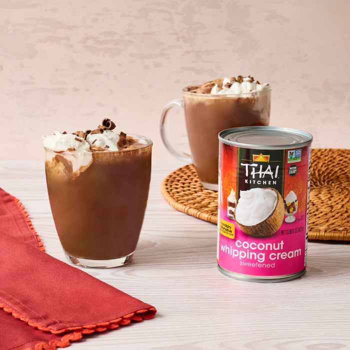 A can of Thai Kitchen coconut whipping cream is featured next to two glasses of hot chocolate topped with whipped cream and chocolate shavings.
