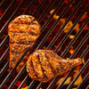 Two pieces of meat are grilling on a hot grill.