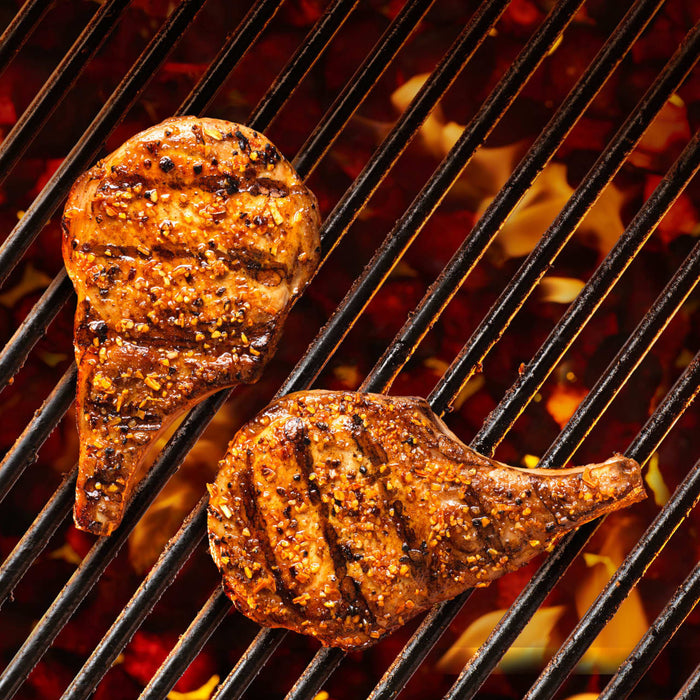 Two pieces of meat are grilling on a hot grill.