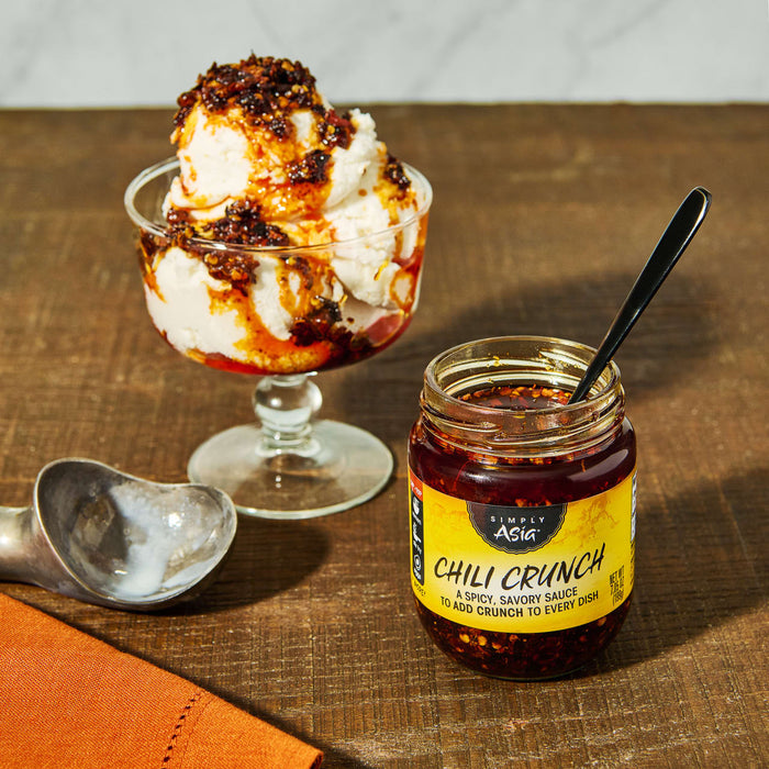 A jar of Simply Asia Chili Crunch sauce next to a bowl of ice cream topped with chili crunch.