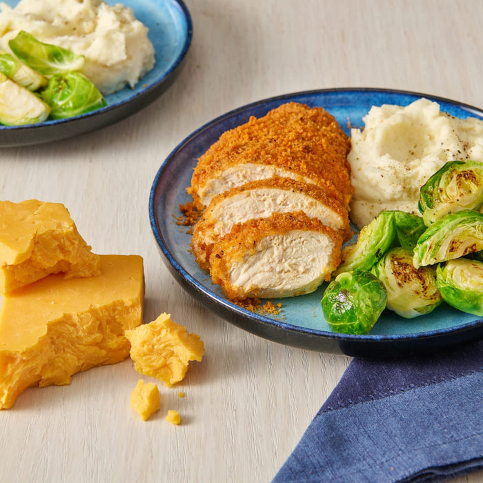 A plate of breaded chicken, mashed potatoes, and brussel sprouts.