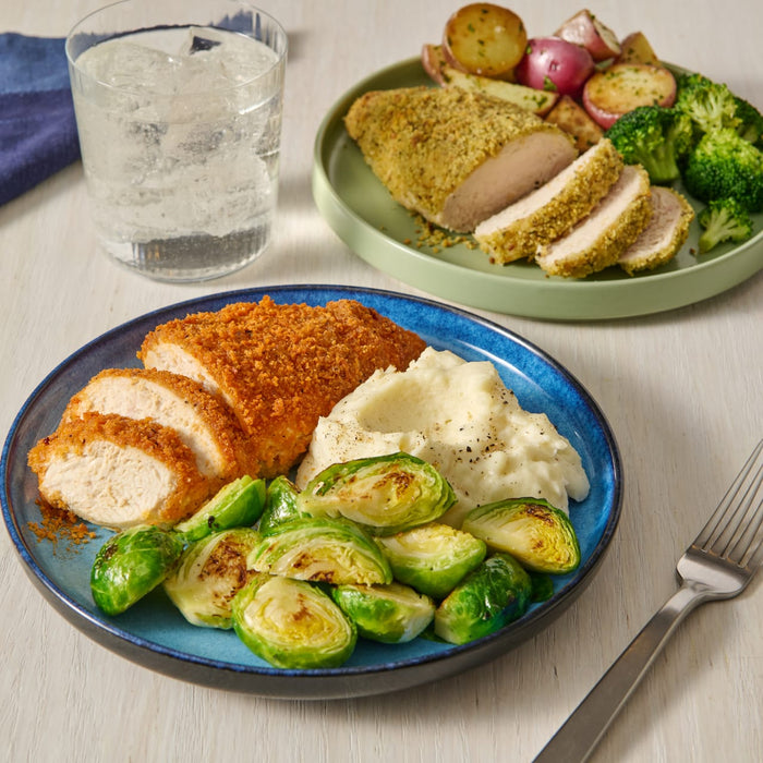 A plate of breaded chicken, mashed potatoes, and brussel sprouts.