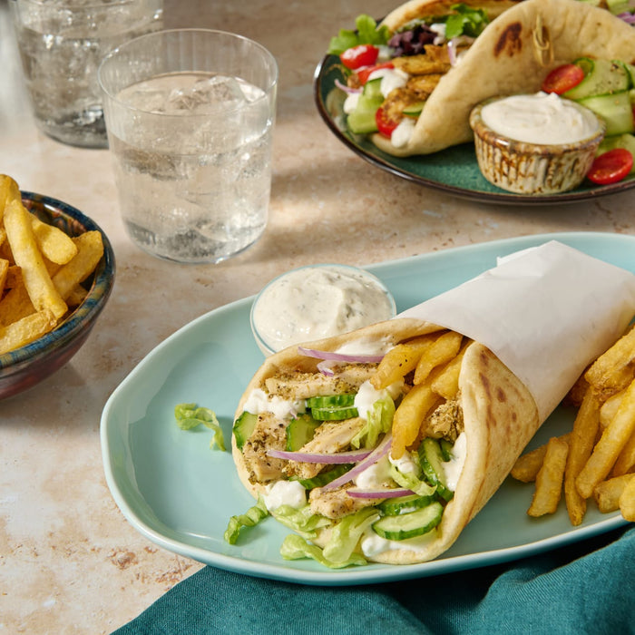 A plate of food with a gyro, fries, and a side of tzatziki sauce.