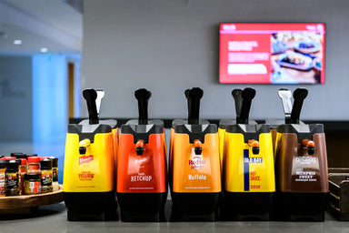 Row of condiment dispensers with visible brand names