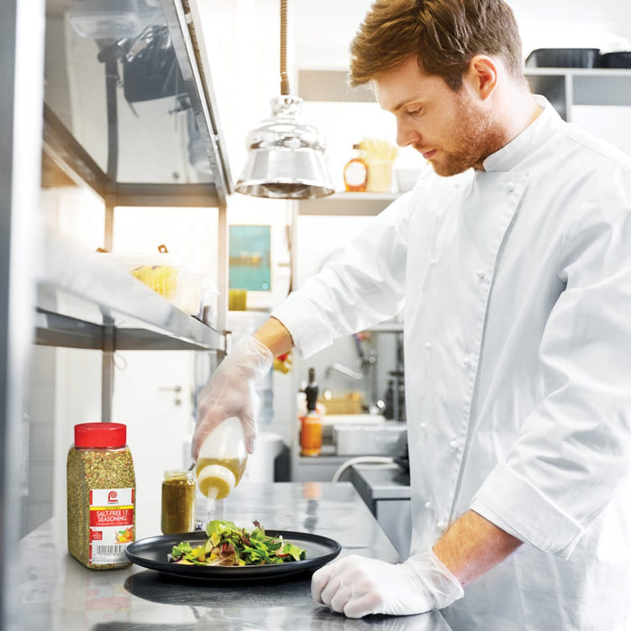 A chef in a white uniform is preparing a salad with Lawry's Salt-Free 17 Seasoning.