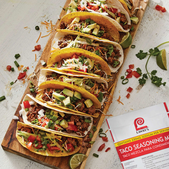 A close-up of Lawry's Taco Seasoning Mix with a plate of delicious tacos.
