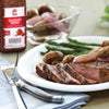 A plate of sliced steak with asparagus, mushrooms, and red onions, with a bottle of McCormick Seasoned Pepper in the background.