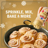 McCormick Cinnamon Sugar is being sprinkled on freshly baked cinnamon rolls, suggesting its versatility for sprinkling, mixing, and baking.
