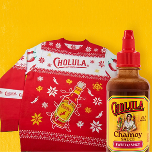 Red 'Cholula' Christmas sweater and bottle of Cholula Chamoy Sauce on a yellow background