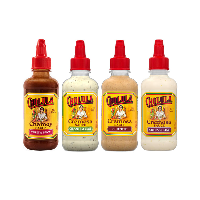 Four bottles of Cholula sauce are lined up against a white background, featuring the Chamoy Sweet &amp; Spicy, Cremosa Cilantro Lime, Cremosa Chipotle, and Cremosa Cotija Cheese flavors.