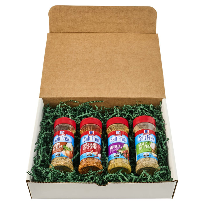 A gift box containing four bottles of Old Bay seasoning nestled in green paper filler.
