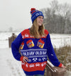 A person wearing an Old Bay themed sweater and hat stands in a snowy landscape.