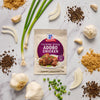 A packet of McCormick Filipino Style Adobo Chicken seasoning mix is surrounded by fresh ingredients like garlic green onions brown sugar and peppercorns.