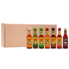 A lineup of seven different bottles of Cholula Hot Sauce, including Original, Green Pepper, Chili Lime, Chili Garlic, Chipotle, Sweet Habanero, and Extra Hot, are displayed in front of a cardboard box.