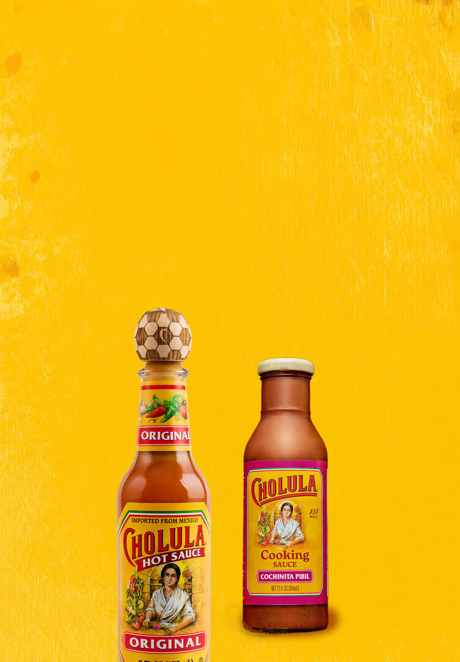 Two bottles of Cholula hot sauce on a yellow background