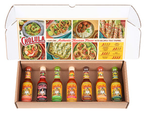 A Cholula Hot Sauce gift set is displayed in its box, featuring seven different flavors: Sweet Habanero, Extra Hot, Chili Lime, Original, Chipotle, Chili Garlic, and Green Pepper.