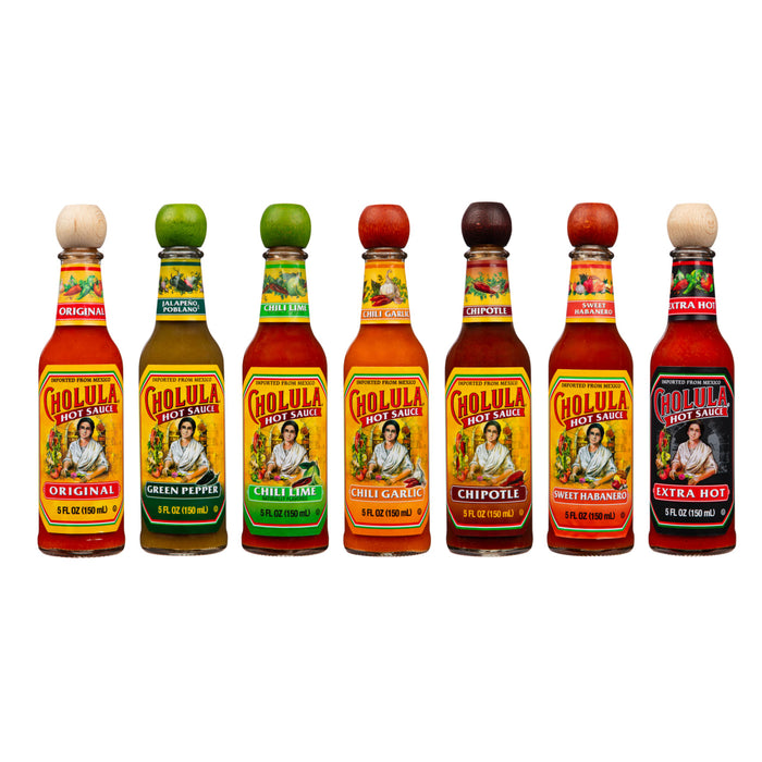 A lineup of seven different bottles of Cholula Hot Sauce, including Original, Green Pepper, Chili Lime, Chili Garlic, Chipotle, Sweet Habanero, and Extra Hot, are displayed side-by-side against a white background.
