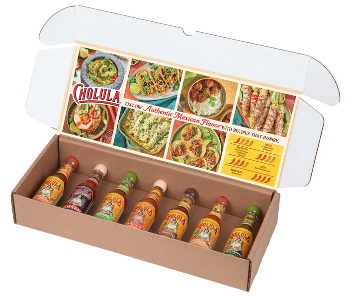 An open gift box reveals a variety pack of Cholula Hot Sauces, with the inside lid featuring inspiring Mexican recipes and a heat scale for the different flavors.