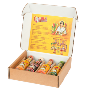 An open cardboard gift box displays four different bottles of Cholula Hot Sauce, including Chili Garlic, Extra Hot, Sweet Habanero, and Green Pepper flavors, against a branded interior.