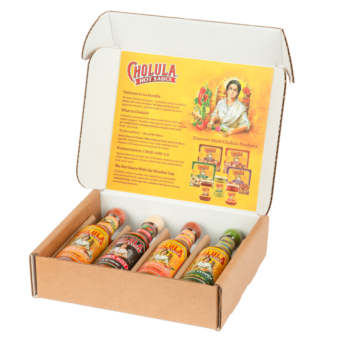 An open cardboard gift box displays four different bottles of Cholula Hot Sauce, including Chili Garlic, Extra Hot, Sweet Habanero, and Green Pepper flavors, against a branded interior.