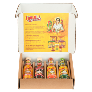 A Cholula Hot Sauce gift set is displayed in an open box, showing four different flavors: Original, Extra Hot, Sweet Habanero, and Green Pepper.
