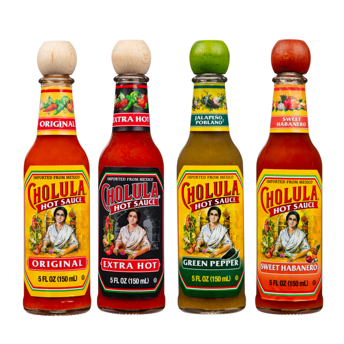 A lineup of four different bottles of Cholula Hot Sauce stands against a black background, showcasing the Original, Extra Hot, Green Pepper, and Sweet Habanero flavors.