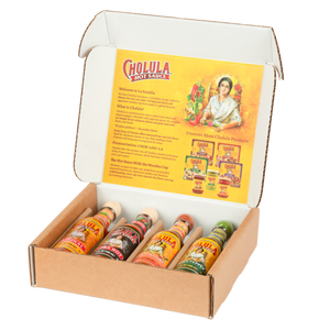 An open gift box displays a variety pack of Cholula Hot Sauce, featuring the Original, Extra Hot, Sweet Habanero, and Green Pepper flavors.