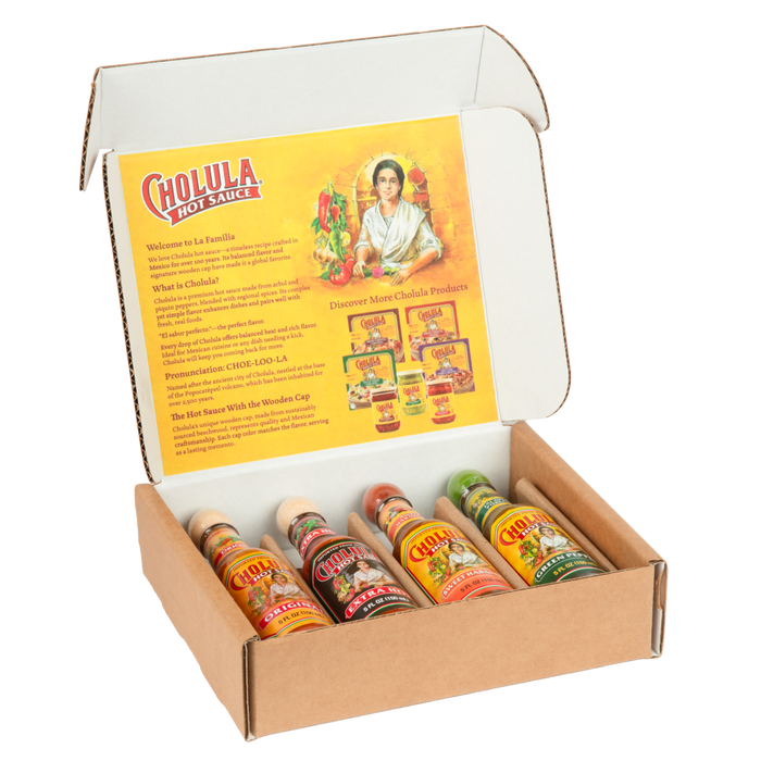 An open cardboard gift box displays four different bottles of Cholula Hot Sauce: Original, Extra Hot, Sweet Habanero, and Green Pepper, with promotional text on the inside of the lid.