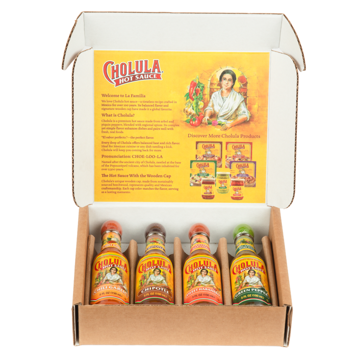 An open gift box displays a Cholula Hot Sauce Variety Pack, featuring Chili Garlic, Chipotle, Sweet Habanero, and Green Pepper flavors, with an informational insert about the brand's history.
