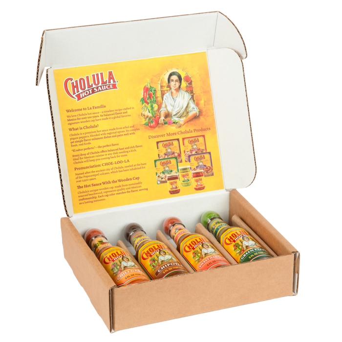 An open gift box of the Cholula Hot Sauce Variety Pack displays four different flavors-Chili Garlic, Chipotle, Sweet Habanero, and Green Pepper-against a black background.