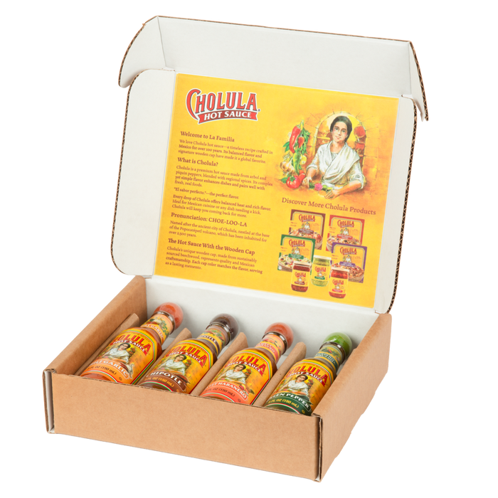 A Cholula hot sauce variety pack is displayed in an open cardboard box, showing four different flavors with their signature wooden caps.