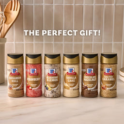 The McCormick Finishing Sugar Bundle, featuring six dessert-flavored finishing sugars like Cinnamon Roll and Strawberry, is displayed on a kitchen counter with text above reading, The Perfect Gift!