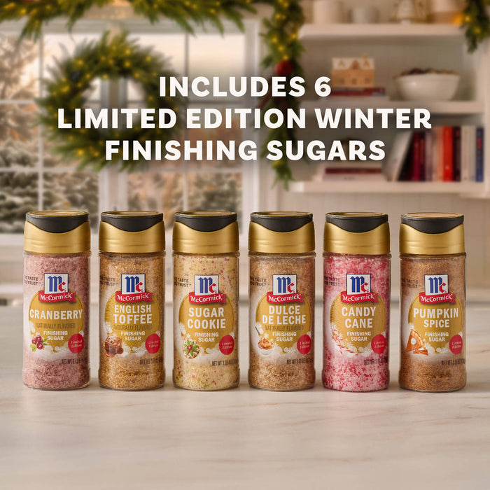 Six bottles of McCormick Limited Edition Winter Finishing Sugars in Cranberry, English Toffee, Sugar Cookie, Dulce De Leche, Candy Cane, and Pumpkin Spice flavors are displayed in a row as part of the Dtcmckvb Winter Finishing Sugars Gift Set.