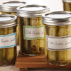 Four jars of dill pickle spears are on a wooden surface.